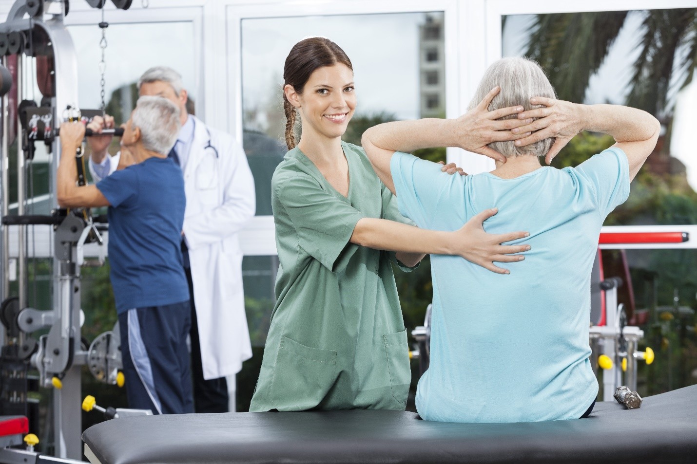 A physiotherapist assisting an elderly patient with a back exercise in a rehabilitation center