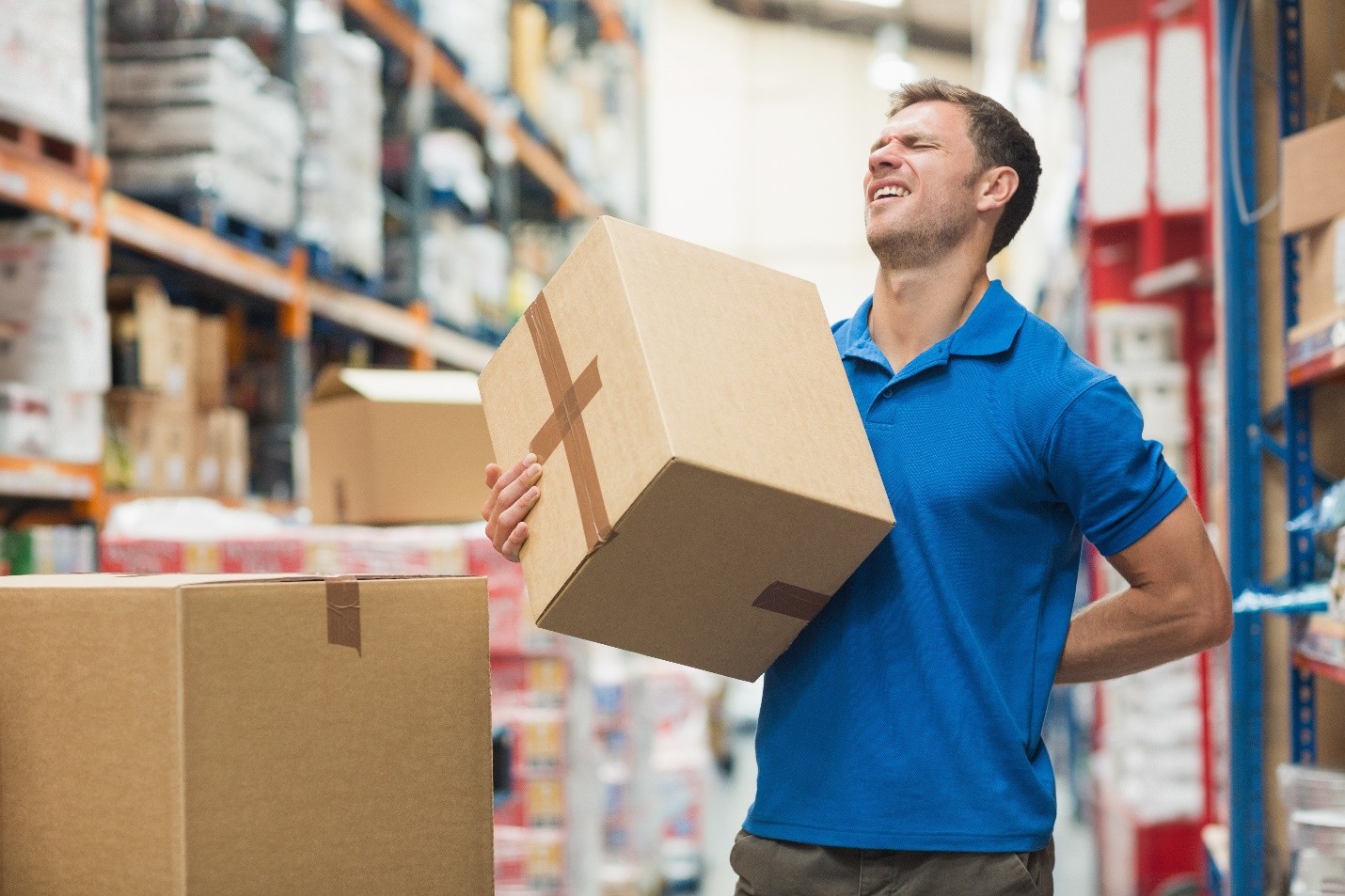 Man lifting a box and clutching his lower back in pain