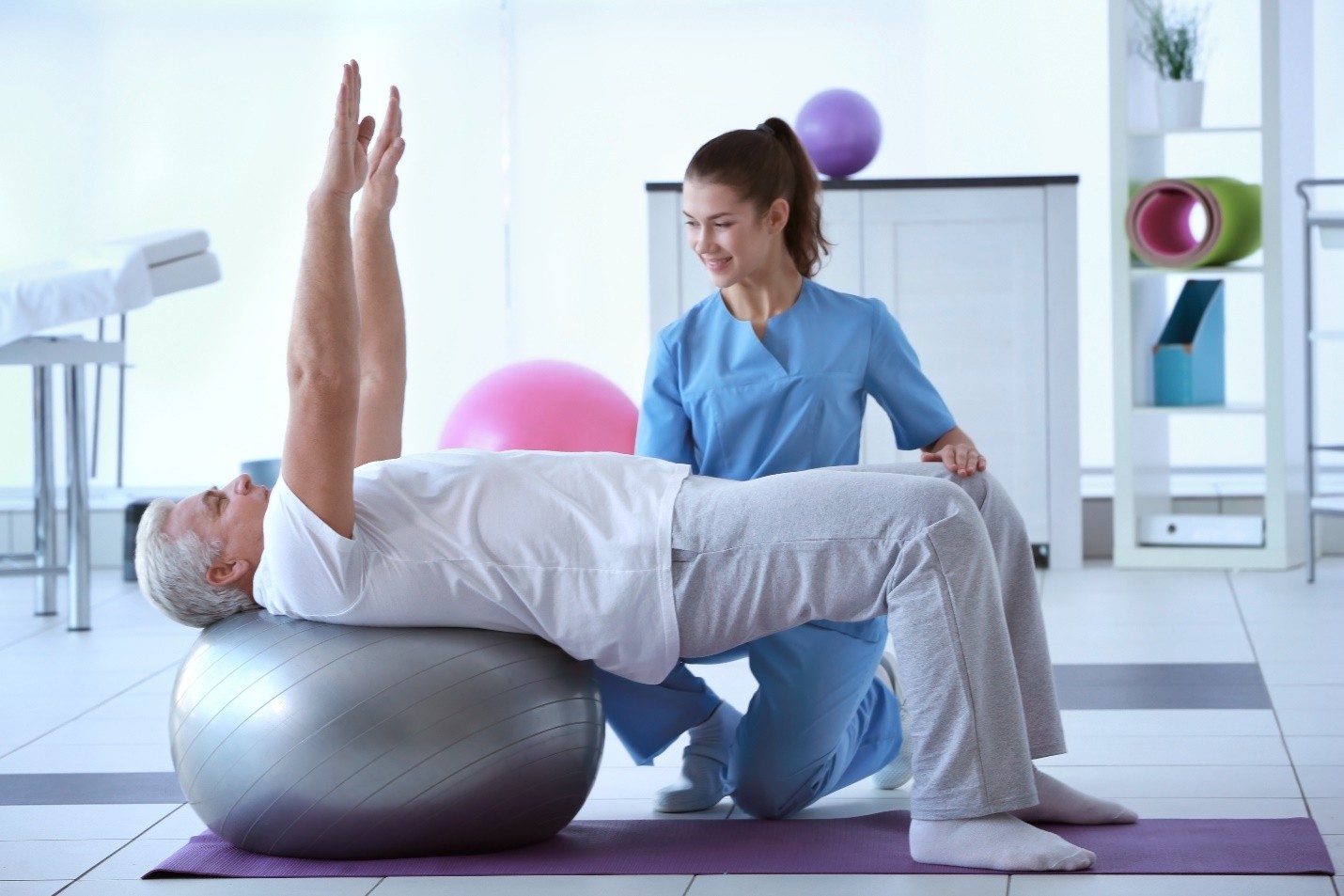 A physical therapist assisting a patient with an exercise on a stability ball