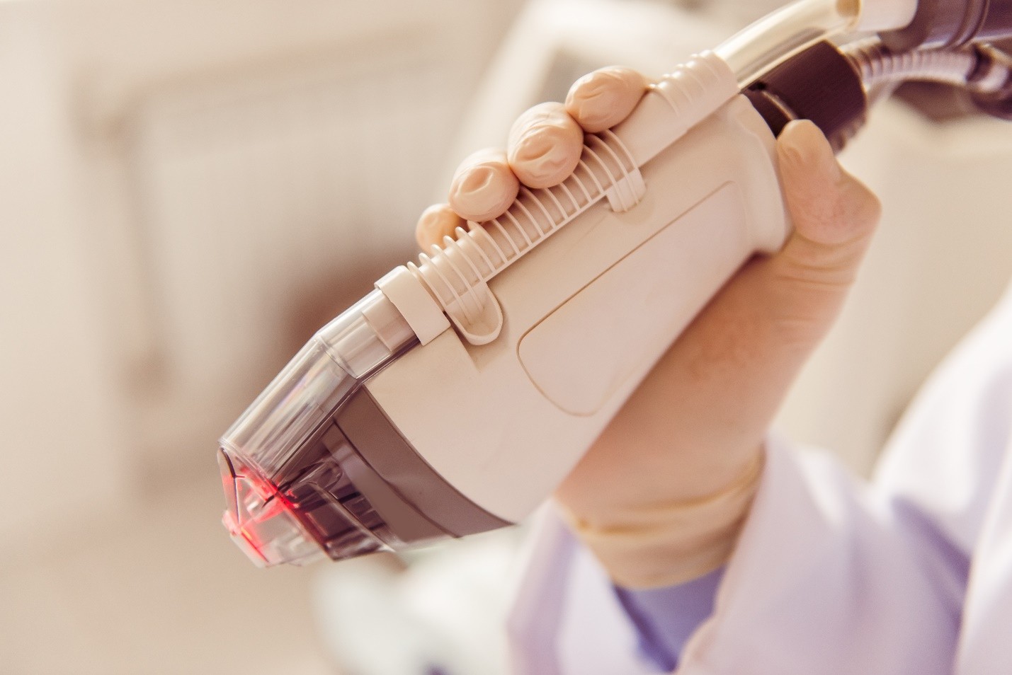 A medical professional holding a handheld device emitting red light