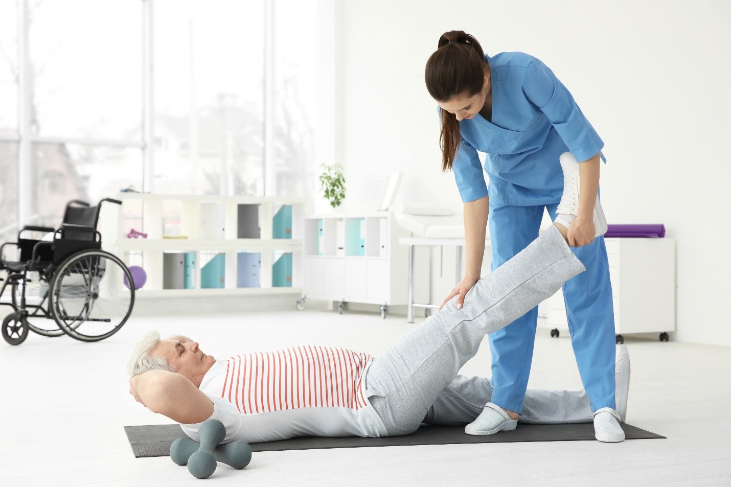A healthcare professional assisting an elderly patient with a leg stretch exercise