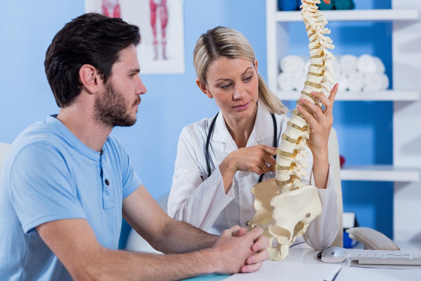 Medical professional showing a spine model to a patient