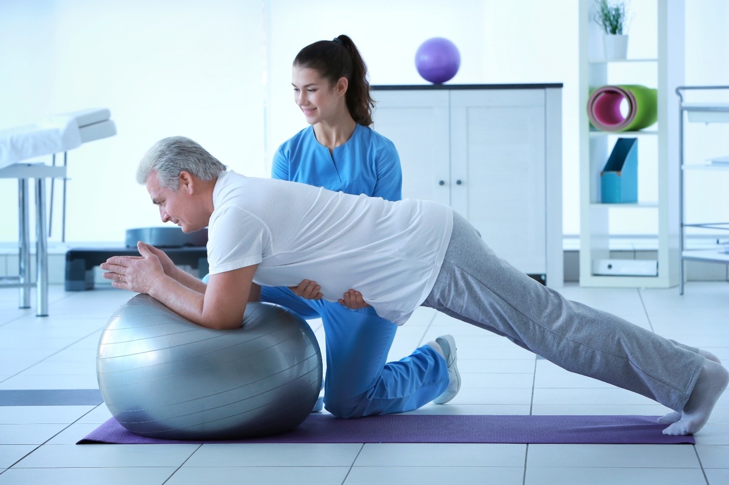A physiotherapist assisting a patient with an exercise using a large stability ball